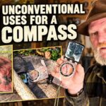 A person holds a base plate compass over a topographic map to measure grid coordinates.